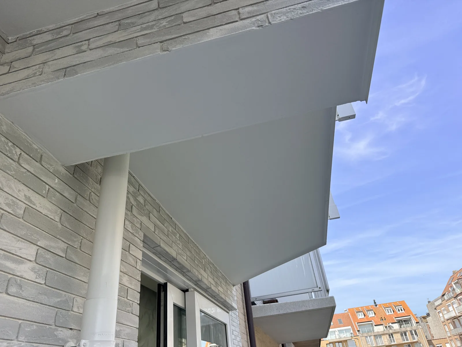 Balkonhemel in gladpleister onder de nieuwe balkons, tegen een gevel in Meldorfer steenstrips