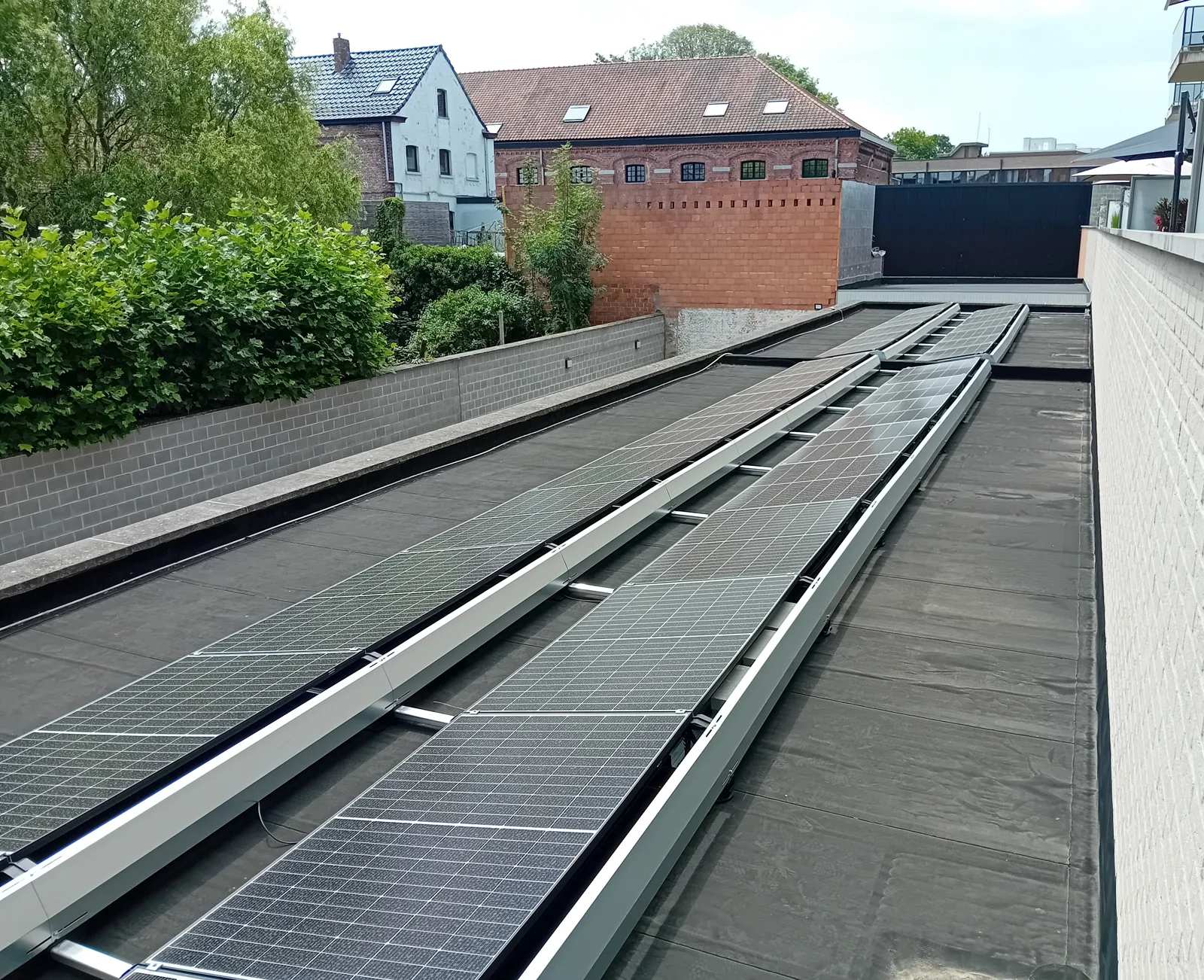 Rijen zonnepanelen op een plat dak tussen de omliggende gebouwen
